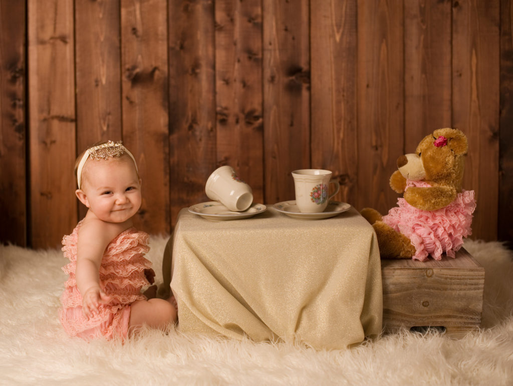 A baby girl having a tea party with her teddy bear.