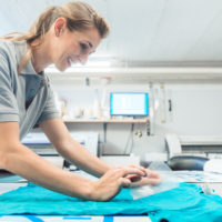 Woman flock printing a T-shirt as promotional item in workshop